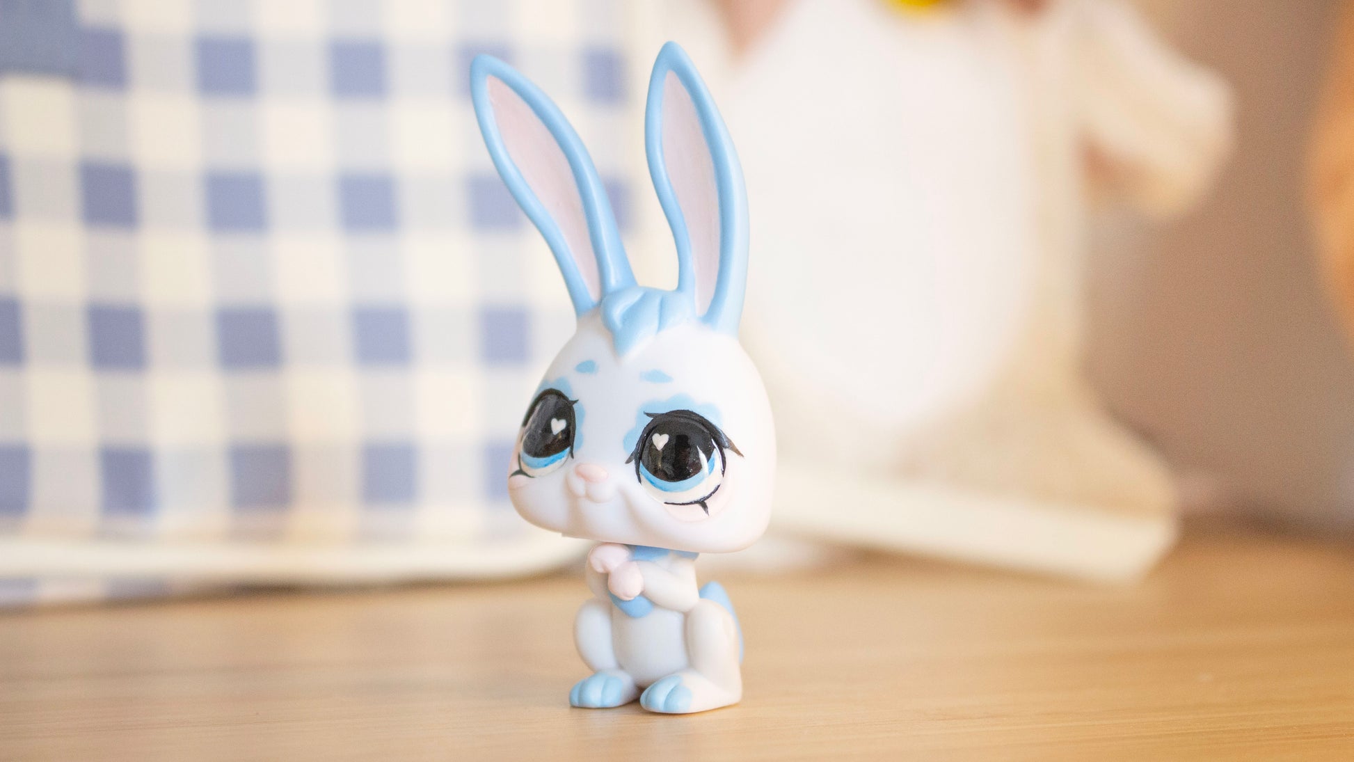 White rabbit figurine with blue accents on a wooden surface
